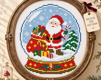 May include: A cross-stitch pattern featuring a Santa Claus inside a snow globe, holding a candy cane and a sack of gifts, framed in an ornate oval frame with a tag labeled DIGITAL PDF PATTERN and the text ArrayofGoods.