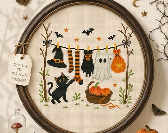 May include: A round cross-stitch embroidery featuring a Halloween scene with a black cat reaching for orange and black striped socks hanging on a clothesline. The design includes a witch hat, a ghost, a pumpkin basket, and bats on a cream fabric.