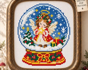 May include: A cross-stitch pattern featuring a snow globe containing an angel with brown hair, a yellow halo, and white wings, wearing a red coat. The globe includes a green Christmas tree and gifts. The base is red with green holly leaves.