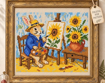 May include: A cross-stitch pattern featuring a rabbit wearing a blue jacket and yellow hat, sitting on a wooden chair while painting a sunflower on an easel. A vase of sunflowers sits on a table nearby. The framed artwork includes a tag labeled DIGITAL PDF PATTERN.
