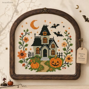 May include: A cross-stitch pattern featuring a haunted house, a crescent moon, bats, and pumpkins framed in a dark wood arch. The design includes orange flowers and green vines on a cream fabric. A tag attached to the frame reads Digital PDF Pattern.