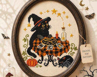 May include: A cross-stitch embroidery in an oval wooden frame featuring a black cat wearing a witch hat at a table with a plaid cloth, tarot cards, a candle, and a potion bottle. A small bat sits below, with stars and a pumpkin nearby.