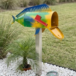 May include: A metal mailbox shaped like a fish, featuring a vibrant yellow, green, and blue gradient finish. It includes a bright red flag on the side, a dorsal fin on top, and a tail fin at the rear, all mounted on a sturdy silver metal post.