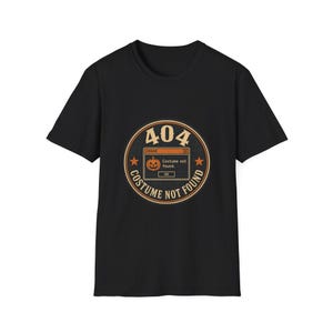 Op de afbeelding: Een zwart t-shirt met korte mouwen en een cirkelvormige afbeelding met de tekst 404 COSTUME NOT FOUND. Het midden toont een computerfoutvenster met een pompoen en de tekst ERROR Costume not found. OK.