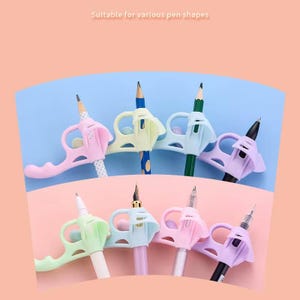 May include: A collection of eight ergonomic silicone pen grips in pastel shades of pink, blue, green, and purple. Each grip features a finger loop and a central opening to hold various writing instruments, including pencils, fountain pens, and ballpoint pens.
