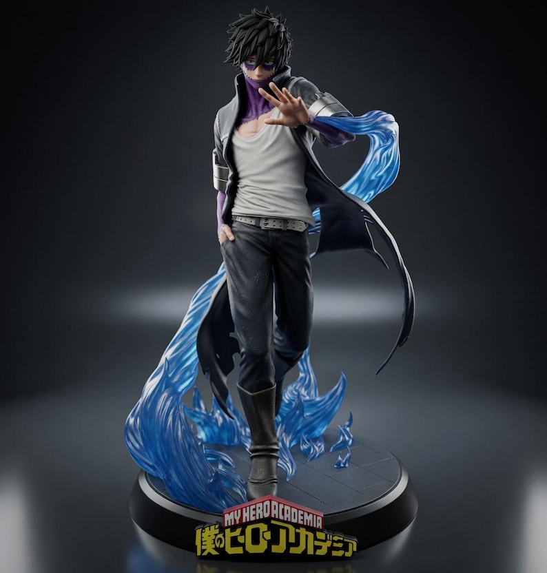 Puede incluir: Figura detallada de un personaje de "My Hero Academia". La figura es de una persona con cabello negro, que lleva una camiseta interior blanca, pantalones negros y un abrigo largo con detalles de llamas azules. La base presenta el logo del programa.