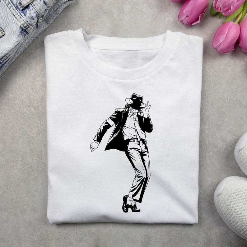 May include: A white crew neck t-shirt featuring a black and white graphic illustration of a person wearing a fedora, suit jacket, and dress shoes, captured in a dynamic dancing pose with one hand raised near the face and one foot pointed.