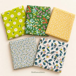 May include: Five folded fabric squares featuring diverse patterns: a lime green with white daisies, a dark green with colorful floral vines, a yellow with tiny white flowers, a light blue with small floral sprigs, and a cream with birds and berries.