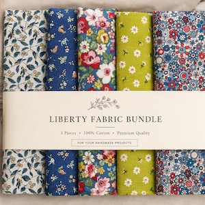 May include: A bundle of five folded cotton fabric pieces featuring diverse floral and botanical patterns in blue, green, red, and white. A paper band wraps the center with the text LIBERTY FABRIC BUNDLE, 5 Pieces, 100% Cotton, Premium Quality.