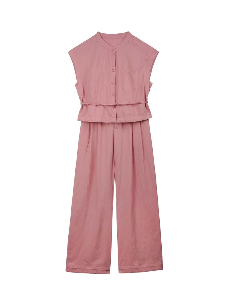 May include: A dusty pink sleeveless jumpsuit featuring a mandarin collar, a button-down front closure, two chest pockets, and a thin matching waist tie. The garment has wide-leg trousers with a pleated front design and a clean, solid-colored finish.