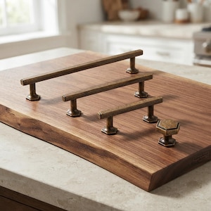 Peut inclure: Un ensemble de quatre poignées de meuble en laiton antique, comprenant trois poignées barres horizontales de longueurs différentes et un bouton hexagonal, tous dotés d'un design géométrique cohérent avec des bases de fixation hexagonales.