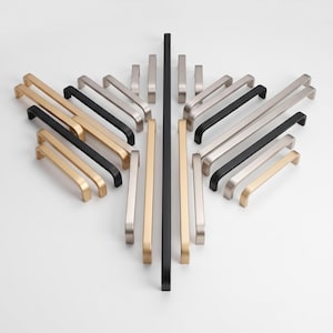May include: A collection of metal cabinet handles arranged in a symmetrical pattern. The hardware features various lengths and finishes, including matte black, brushed gold, and silver tones, all with a simple, straight, and functional design.