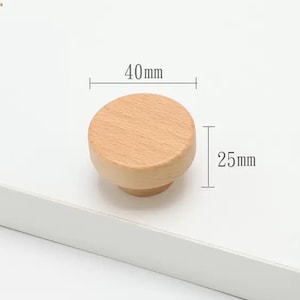 May include: A round, light-coloured wooden cabinet knob with a smooth, natural grain finish. The knob features a diameter of 40mm and a height of 25mm, as indicated by the technical dimension lines overlaid on the product image.