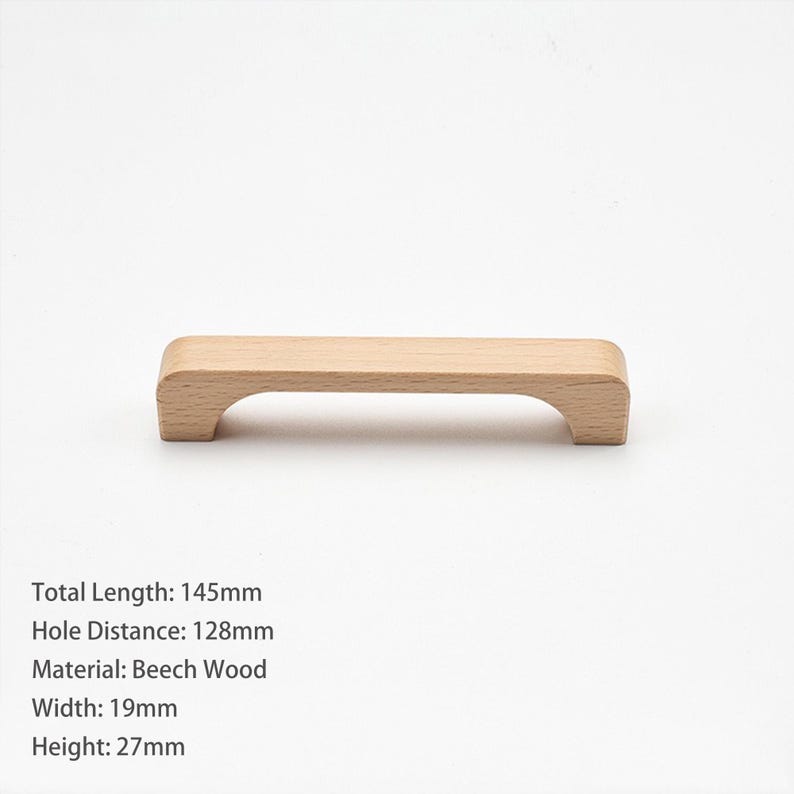 May include: A light-colored wooden cabinet handle with a smooth, rectangular top and curved ends. The text specifies a total length of 145mm, a hole distance of 128mm, a width of 19mm, a height of 27mm, and that it is made of beech wood.