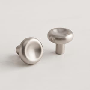 May include: Two circular cabinet knobs with a smooth, brushed silver-tone metallic finish. Each knob features a rounded, slightly concave top surface and a cylindrical base, providing a clean and uniform appearance for furniture hardware.
