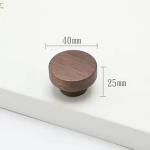 May include: A round, dark brown wooden cabinet knob with a visible wood grain pattern. The knob has a diameter of 40mm and a height of 25mm, as indicated by the technical measurement lines and text displayed directly on the image.
