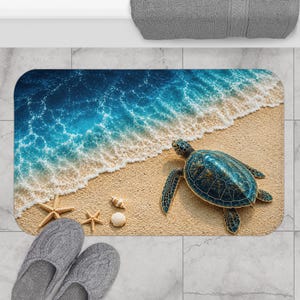 May include: A rectangular bath mat featuring a high-resolution print of a sea turtle on a sandy beach with ocean waves washing ashore. The design includes two starfish and two seashells on the sand near the turtle, rendered in blue and tan.