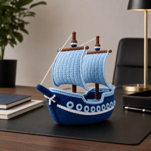 Peut inclure: Un voilier crocheté à la main, dans les tons de bleu, marron et blanc. Le bateau présente des voiles bleu clair, une coque bleu foncé avec des accents blancs et des mâts bruns. Cet objet de décoration sur le thème nautique est un ajout charmant.