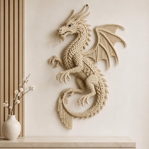 May include: A beige macrame wall hanging shaped like a dragon with intricate knotted patterns, a long curved tail with fringe, detailed wings, and sharp claws. The dragon is depicted in a dynamic pose with its head turned and mouth slightly open.