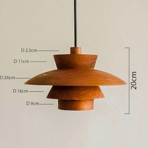 May include: A tiered wooden pendant light fixture with a natural brown finish. The lamp features four distinct stacked circular sections of varying diameters, including 2.5 cm, 11 cm, 26 cm, 16 cm, and 9 cm, with a total height of 20 cm.