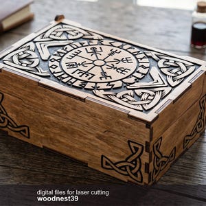 Puede incluir: Caja de madera con intrincados diseños de nudos celtas y rosa de los vientos cortados con láser. La caja está teñida de un color marrón cálido y presenta tallas detalladas en la tapa y las esquinas. El texto "digital files for laser cutting woodnest39" es visible.