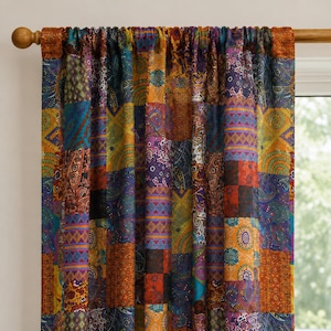 Può includere: Una tenda con un vivace design patchwork composto da vari pannelli rettangolari nei toni dell'arancione, viola, blu e giallo. Il tessuto presenta intricati motivi paisley, geometrici e floreali su tutta la superficie, appesa a un bastone in legno.