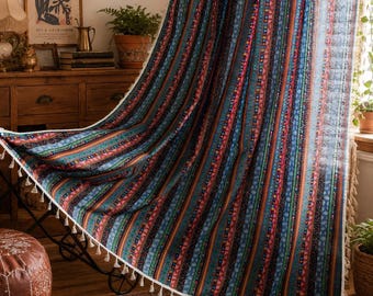 May include: A semi-sheer curtain panel featuring a vertical striped pattern in shades of blue, red, orange, and green. The fabric displays various geometric motifs within the stripes and is finished with a decorative white tassel fringe trim.