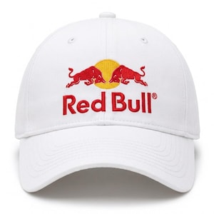 May include: White baseball cap featuring the Red Bull logo. The logo includes two red bulls facing each other above the red text "Red Bull". The cap has a curved brim and a button on top.