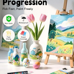 K&ouml;nnte beinhalten: Acryl-Farbstifte mit schwarzem Geh&auml;use und zwei Spitzen, pr&auml;sentiert mit bemalten Flaschen, einem Ei, einer Handyh&uuml;lle und einer Leinwand auf einer Holzstaffelei. Text: The Art of Progression, Pick Fast, Paint Freely, Non-toxic, Waterproof, Fast Drying, Great Coverage.