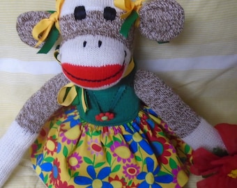 Muñeca clásica de mono con tacón rojo "Flower Power" con falda y collar florales.