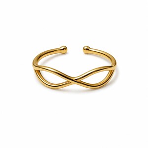 Op de afbeelding: Een goudkleurige open ring met een doorlopend oneindigheidssymbool. De band is gemaakt van glad, gepolijst metaal met afgeronde, bolvormige uiteinden bij de opening, wat een slanke en symmetrische lusstructuur vormt die de oneindigheidsvorm creëert.