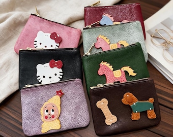 Puede incluir: Un conjunto de seis estuches rectangulares con cremallera en varios colores, incluyendo rosa, negro, morado, rojo, verde y marrón oscuro. Cada estuche presenta un aplique de cuero único, como una cara de gato, un caballo o un perro con hueso.