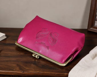 Puede incluir: Un bolso de mano color magenta vibrante con un cierre de boquilla en acabado de latón antiguo. La parte frontal del bolso muestra un diseño gráfico sutil y grabado de dos formas estilizadas y simétricas con detalles de líneas.