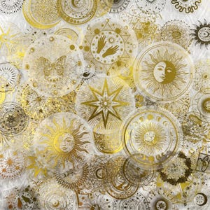 Può includere: Una collezione di adesivi circolari trasparenti con disegni celesti in lamina d'oro, tra cui soli, lune, stelle, farfalle e mani. I motivi complessi sono sovrapposti, mostrando vari temi astrologici e cosmici.