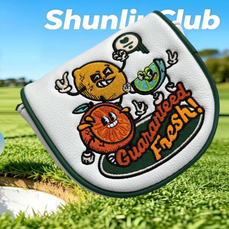 Puede incluir: Una funda para putter blanca con ribete verde oscuro que presenta personajes de c&iacute;tricos de dibujos animados bordados, incluyendo un lim&oacute;n, una lima y una naranja. El texto "Guaranteed Fresh!" est&aacute; bordado en naranja y "ShunliClub" aparece arriba.