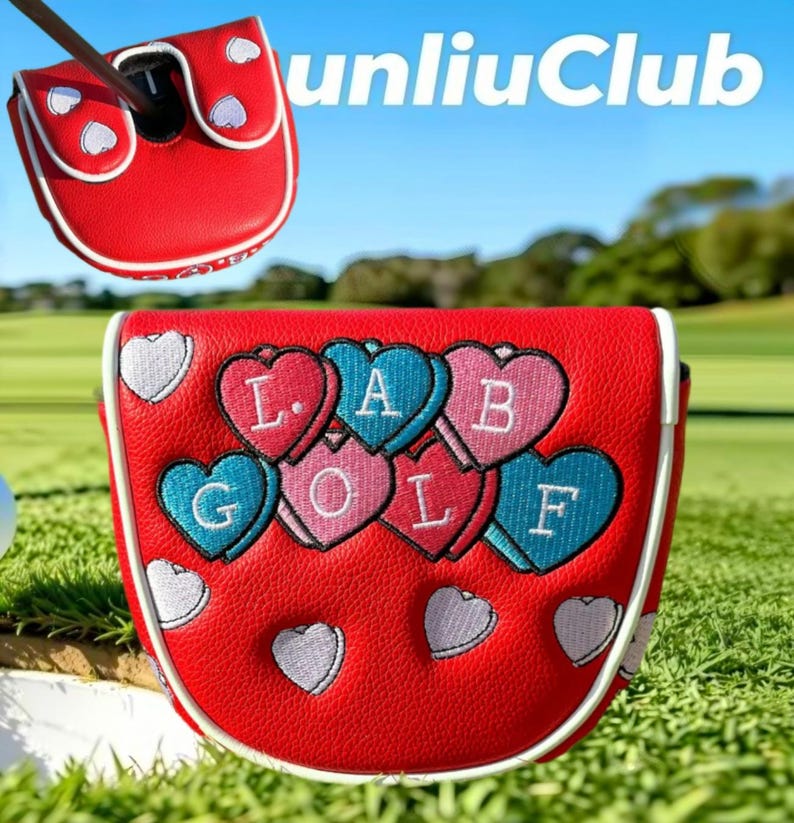Op de afbeelding: Een rode golfputter-headcover met witte biezen en geborduurde hartjes in roze, blauw en wit. De hartjes tonen de letters L, A, B, G, O, L, F in wit stiksel. De hoes heeft een gestructureerd oppervlak en een magnetische sluiting.