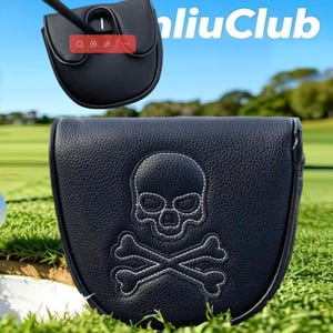 May include: A black textured putter headcover featuring a white stitched skull and crossbones design on the front. The cover has a rounded shape and is shown in two views, with a golf club shaft visible in the upper portion of the image.