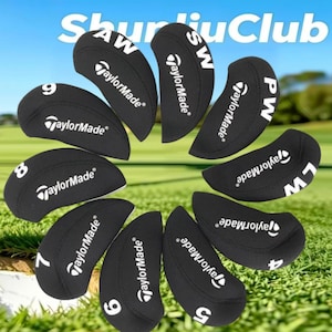 Op de afbeelding: Een set zwarte TaylorMade golfijzer-headcovers gerangschikt in een cirkelvormig patroon. Elke cover bevat witte tekst die het clubnummer of type aangeeft, waaronder 4, 5, 6, 7, 8, 9, PW, AW, SW en LW, samen met het TaylorMade-logo.