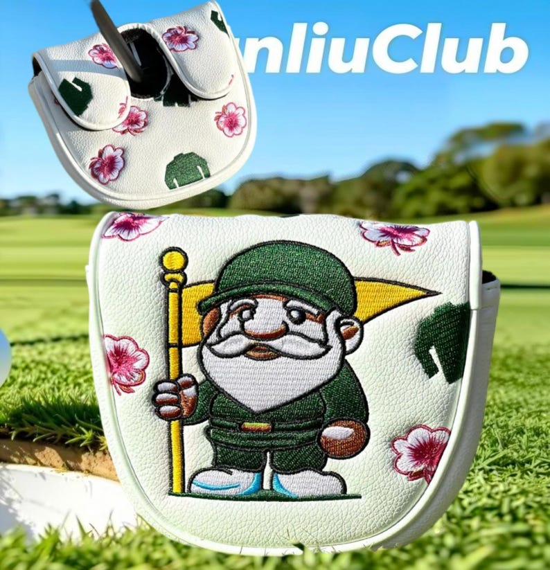 Op de afbeelding: Een witte golfputter headcover met een geborduurde kabouter in een groen uniform die een gele vlag vasthoudt. De hoes is versierd met kleine roze hibiscusbloemen en groene bladpatronen. De tekst "nliuClub" is bovenaan zichtbaar.