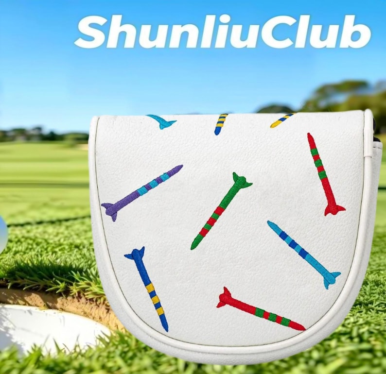 May include: A white golf putter headcover featuring an embroidered pattern of colorful golf tees in red, green, blue, purple, and yellow. The text ShunliuClub is printed in white at the top of the image against a blurred green golf course background.