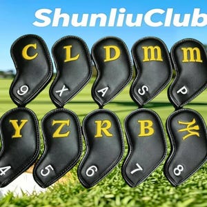 May include: A set of ten black golf iron head covers with yellow embroidered letters and white numbers. The covers feature the text ShunliuClub at the top. Each cover displays a unique letter and number combination, including 9C, XL, DA, mS, mP, Y4, Z5, R6, B7, and M8, arranged in two rows.