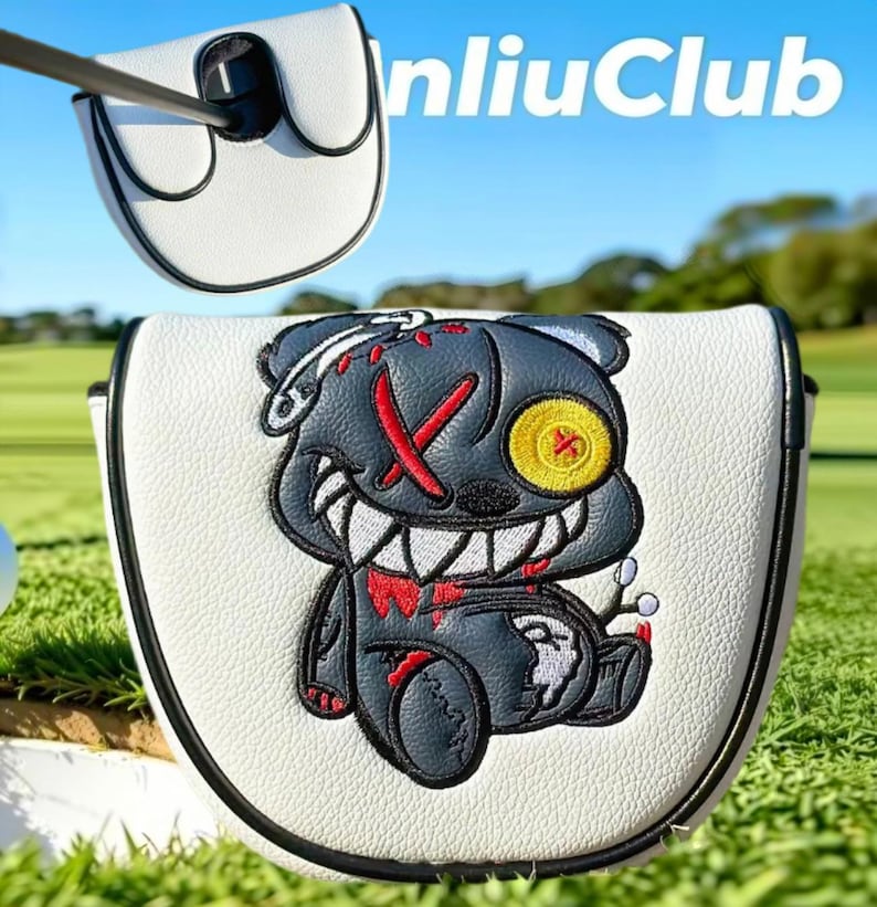 May include: A white mallet putter headcover with black trim featuring an embroidered dark gray bear character with a yellow button eye, red stitched X eye, and sharp white teeth. The text "nliuClub" is visible in the upper right corner.
