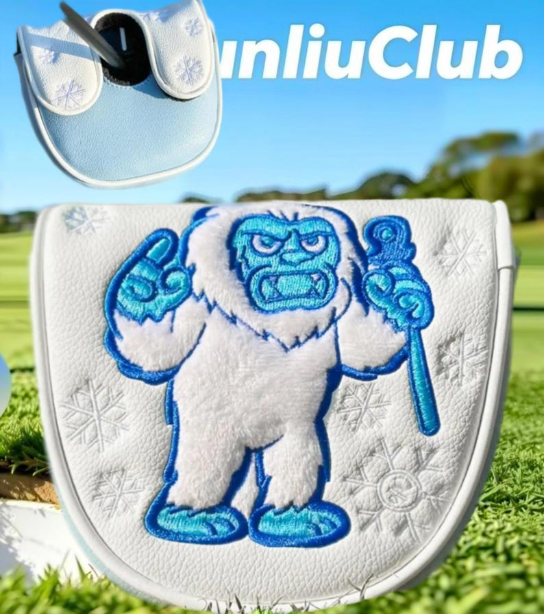 May include: A white golf putter headcover featuring an embroidered yeti character in blue and white tones, holding a staff. The cover is decorated with stitched snowflake patterns and includes a smaller view of the top with the text unliuClub.