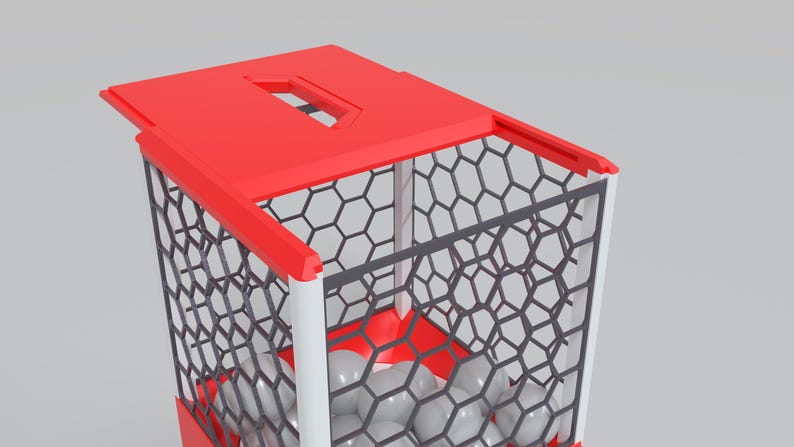 May include: A red and white geometric container with a hexagonal pattern and a red top. The container holds several gray spheres. The design is modern and minimalist.