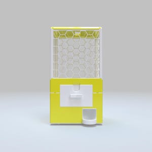 May include: A yellow and white gumball machine with a hexagonal pattern on the front. The machine has a white dispensing area and a small white cup at the bottom. The top of the machine is also yellow.