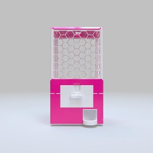 May include: A bright pink gumball machine with a white honeycomb pattern in the viewing area. The machine has a white dispensing door and a small white cup at the bottom. The top of the machine is also pink.