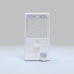 May include: A white gumball machine with a clear, hexagonal grid pattern on the top section. The machine has a rectangular shape with a dispensing slot and a small collection area at the bottom. The overall design is clean and modern.