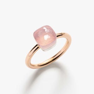 Puede incluir: Anillo de oro rosa con una gema rosa pálido cuadrada y facetada. La gema está engastada sobre una base plateada, y la banda es de oro pulido y cálido. Se muestra sobre un fondo blanco.