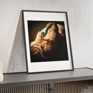 Peut inclure: Une impression d'art encadrée représentant une illustration sombre et dramatique de deux silhouettes enlacées. L'une porte un gant bleu clair, avec une lumière dorée chaude soulignant leur peau sur un fond noir profond, sous un cadre noir.