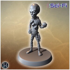 May include: A gray, monochromatic figurine of an extraterrestrial character standing on a circular base. The figure wears a hooded top with a bandolier of canisters, pants with a holster, and holds a small spherical object. The text Sci-Fi is visible.